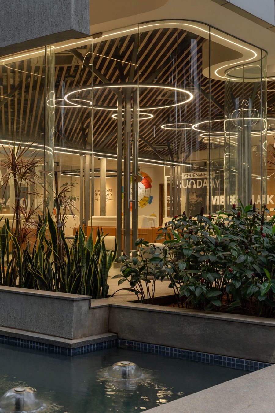 Water feature and glass pavilion illuminated at night